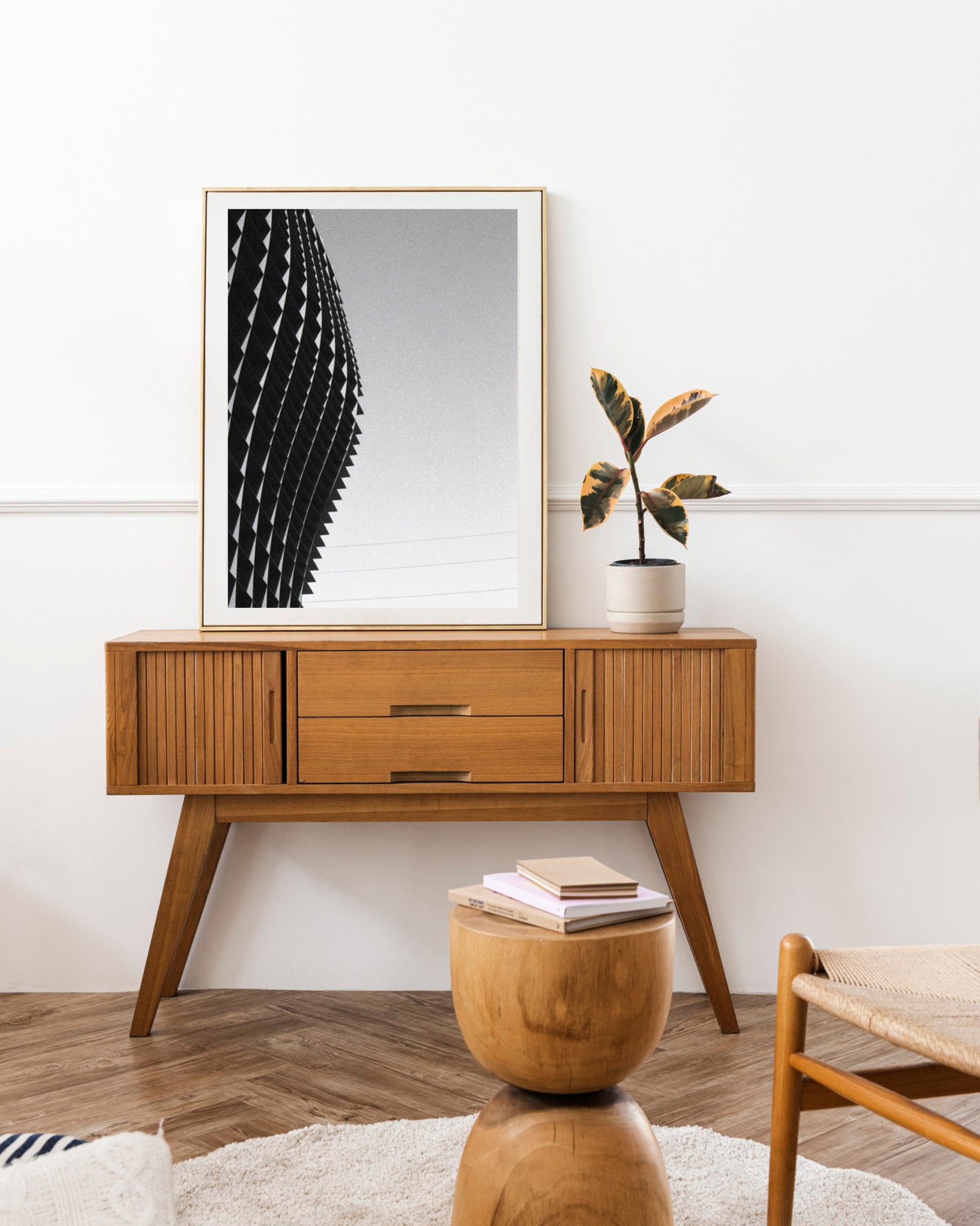 Wooden console table with a plant and framed artwork in a room setting.
