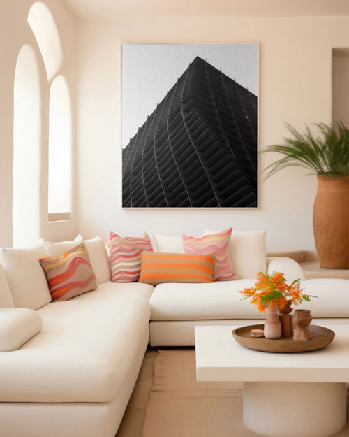 Modern living room with a white sofa, colorful pillows, and a large abstract painting on the wall.