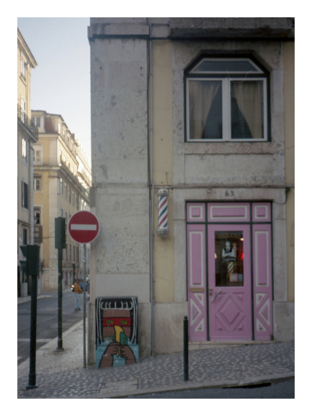 Street scene with a building featuring a pink door and a barber pole in Portugal.