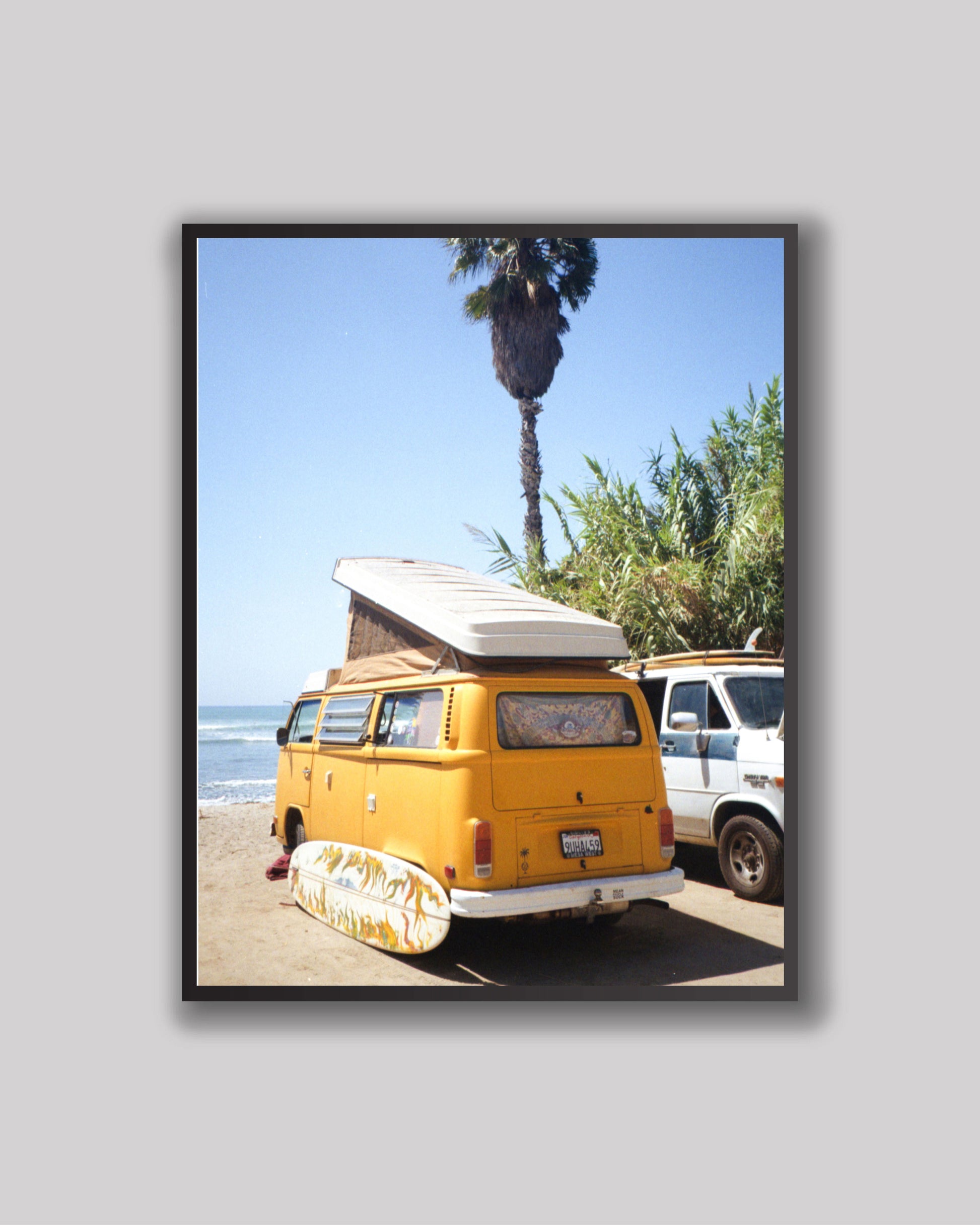 Yellow van with a surfboard on a beach with palm trees in the background